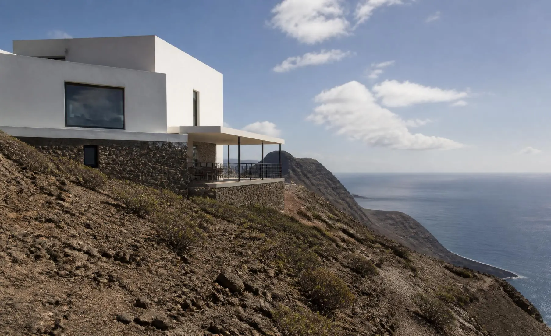 Vivienda contemporánea integrada en una ladera volcánica frente al Atlántico