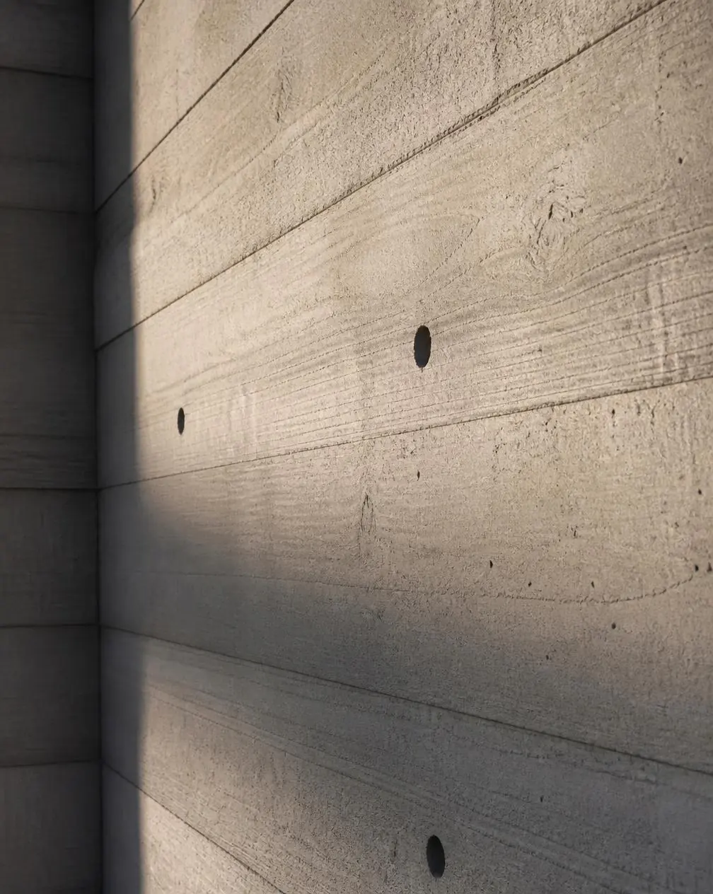 Muro de hormigón encofrado con veta de madera y agujeros de anclaje